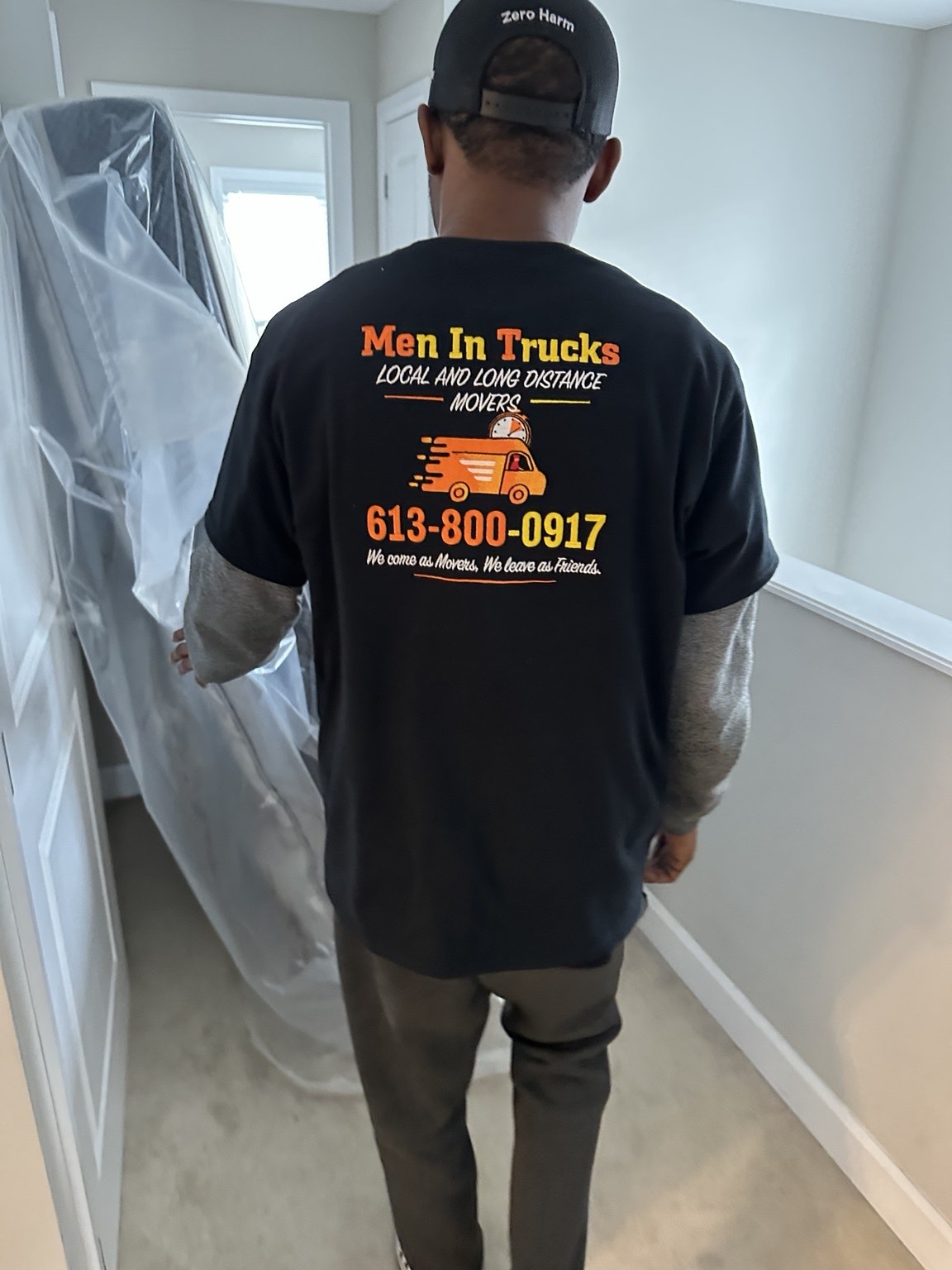 Men In Trucks mover carrying a plastic-wrapped mattress through an Ottawa home hallway