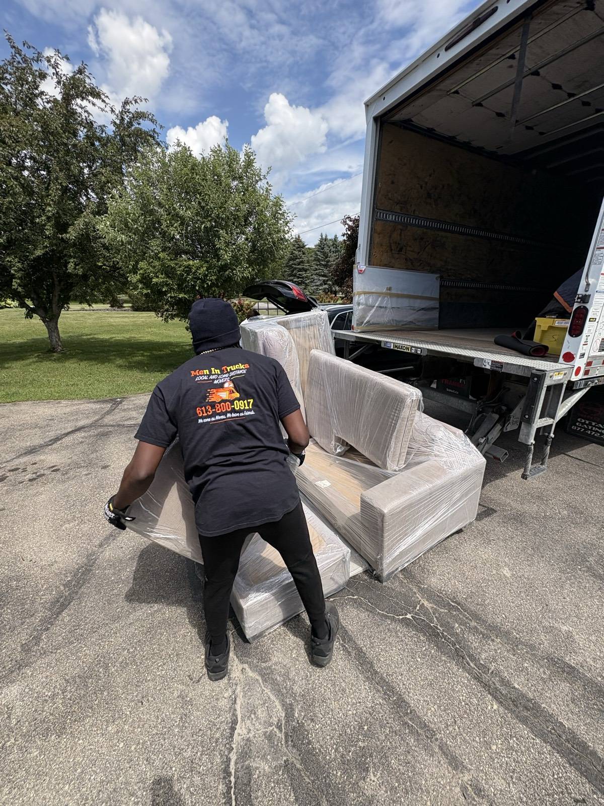 Men In Trucks mover carrying a heavy blanket-wrapped piece to the truck