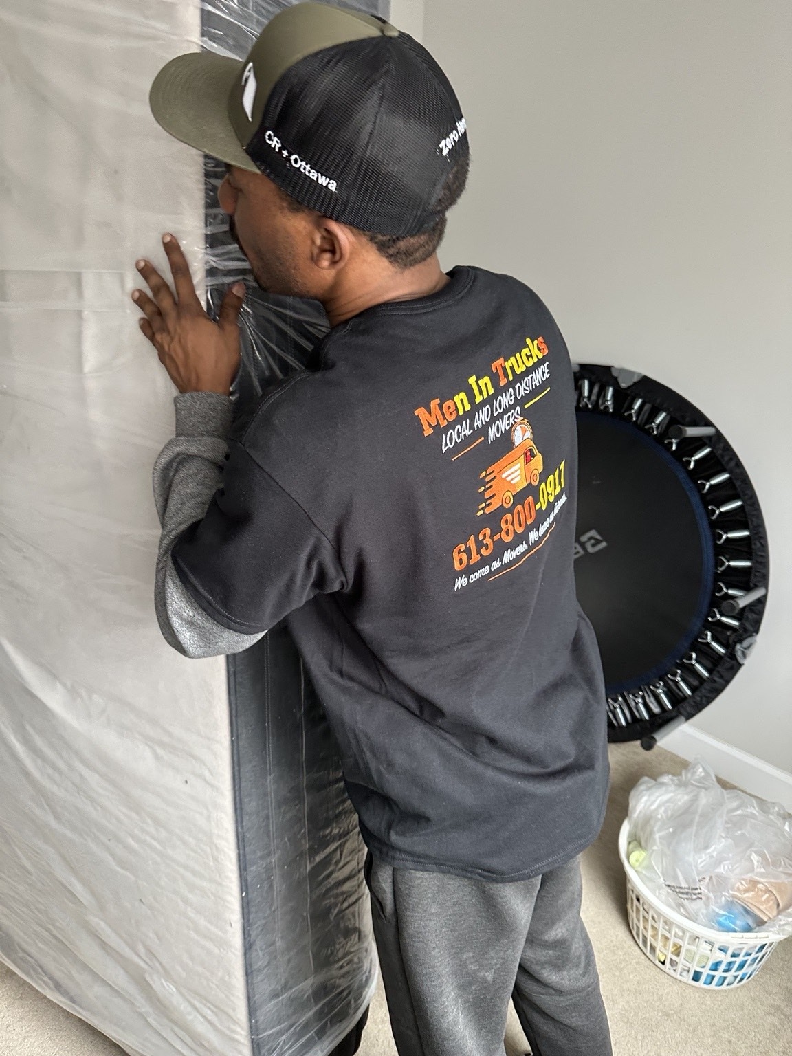 Men In Trucks crew member wrapping a mattress in protective plastic before loading