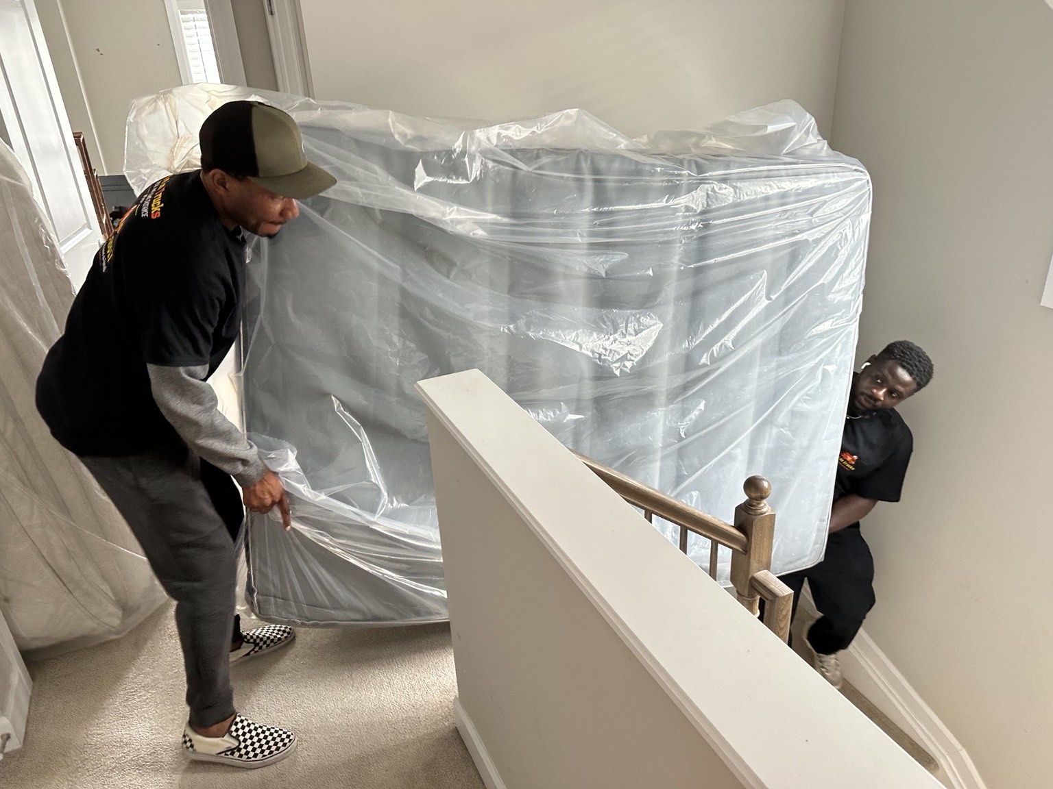 Two movers carrying a wrapped mattress up a staircase during a residential move in Ottawa