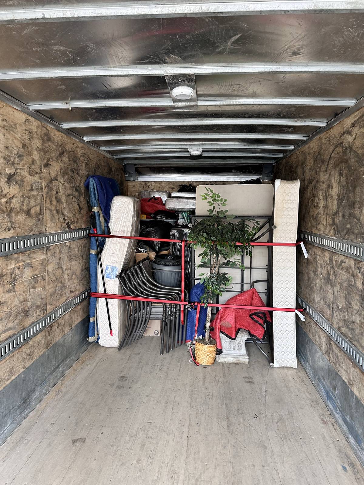 Blanket-wrapped furniture strapped securely inside a Men In Trucks truck for storage